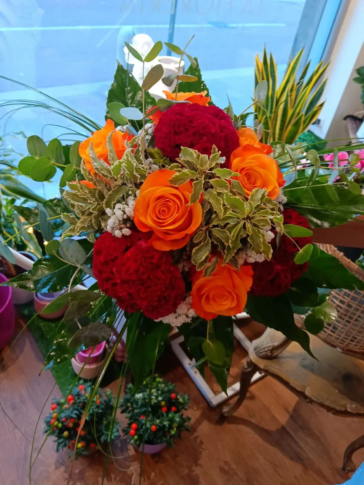 Bouquet di rose rosse e arancioni con verde decorativo