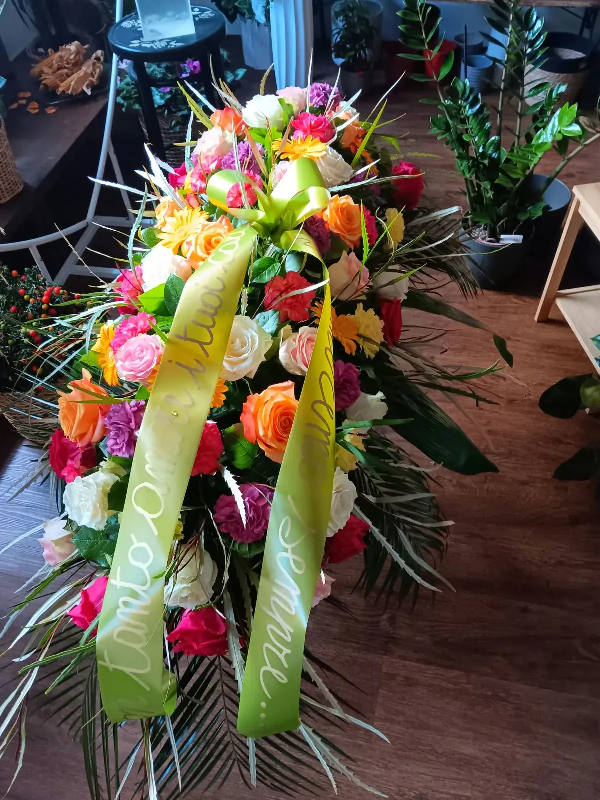 Composizione funebre con fiori colorati e nastro giallo
