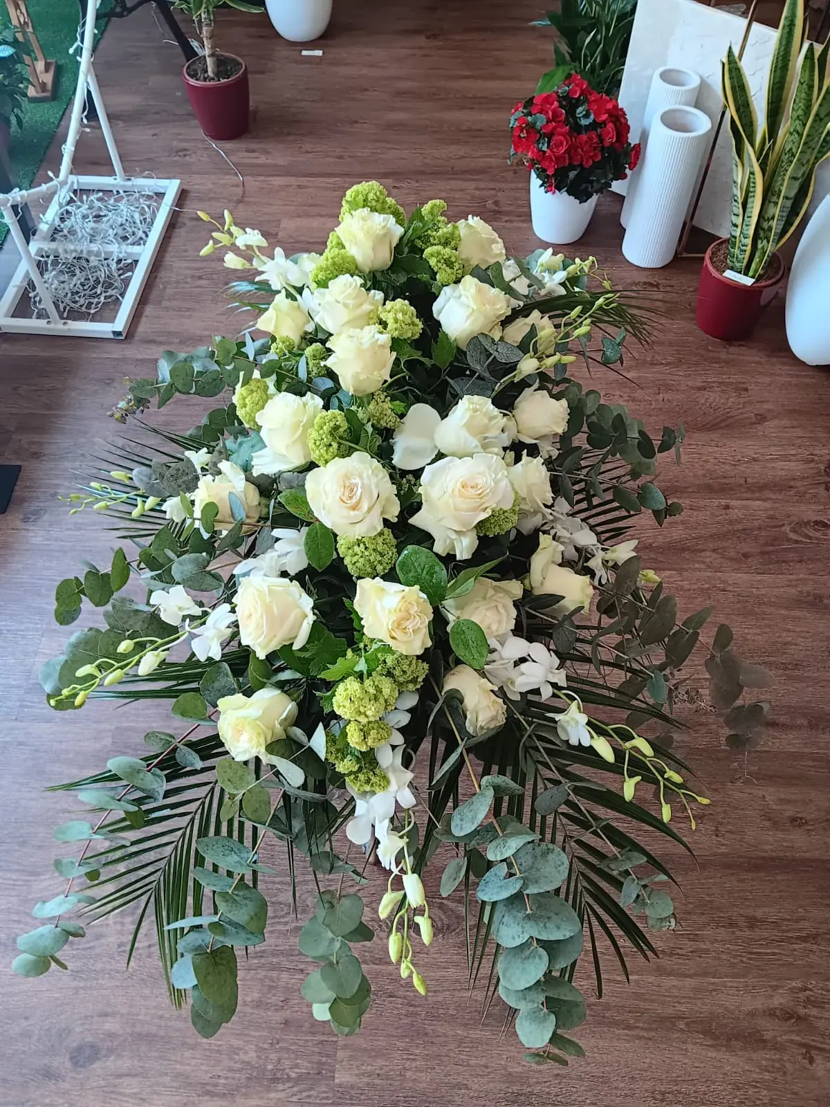 Composizione funebre di rose bianche e verde ornamentale
