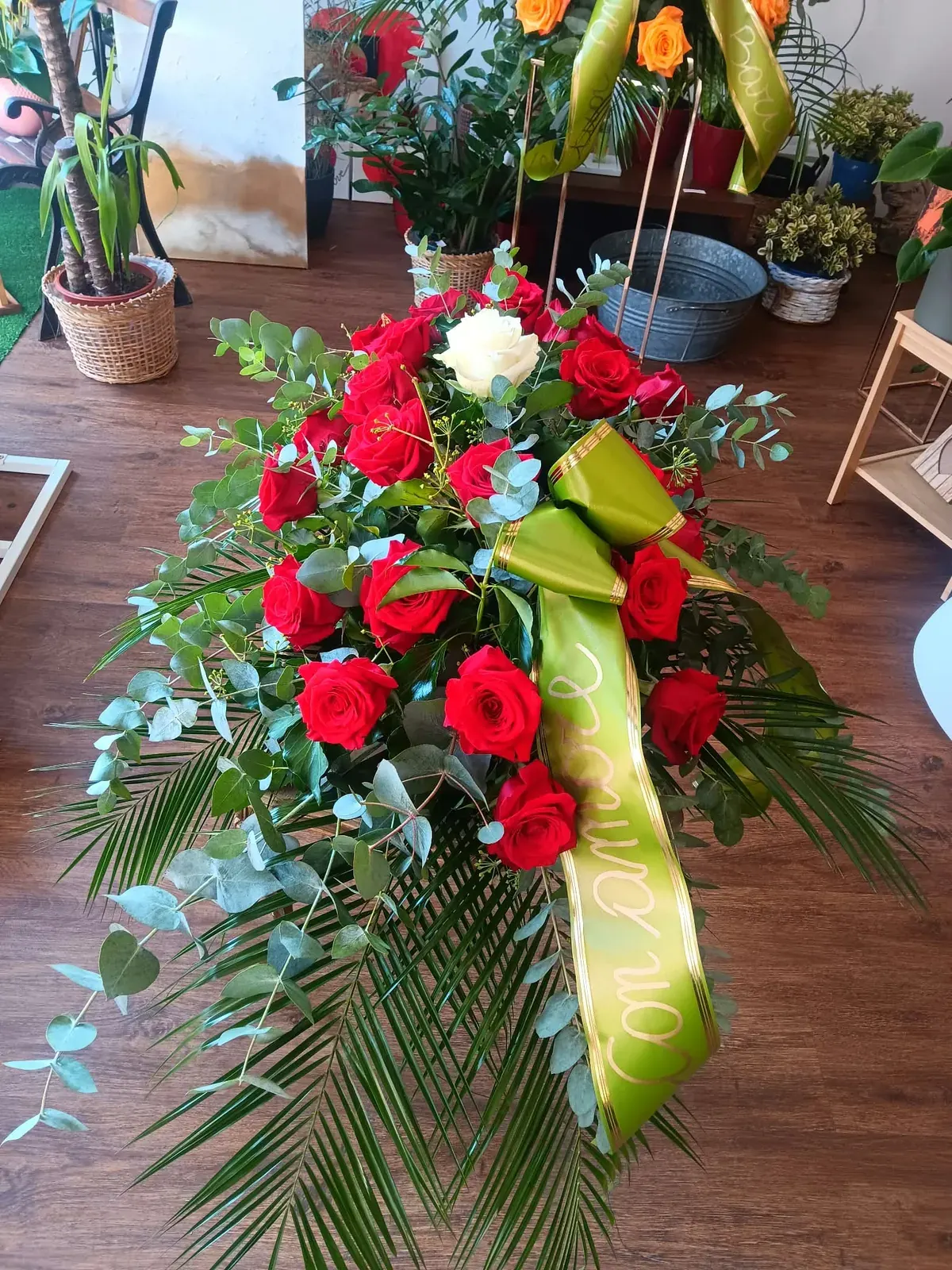 Composizione funebre con rose rosse e nastro verde